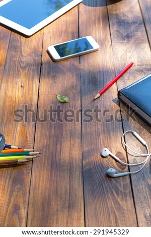 Working desk of professional designer.\
Aged handmade wooden desk from above view cropped laptop tablet PC coffee mug color pencils tree leaf in center of composition