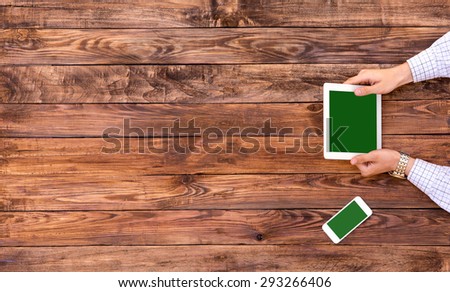 Self-employed man working at vintage wood cafe table.\
Man working at vintage rough wooden desk directly from above browsing electronic gadget mobile office phone paved road on background  white shirt
