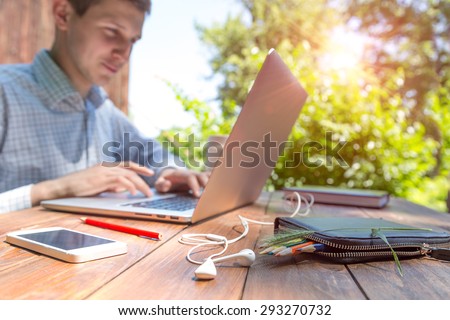 Working man inspired by nature.\
Businessman working on laptop with happy inspired face on green terrace of suburban cottage at brown natural timber wood desk back-light sun from behind