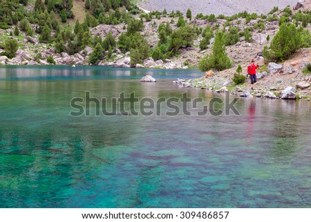 Hiker Walking on Footpath beside Shore Azure Mountain Lake Transparent Water Bottom Stones Well Visible