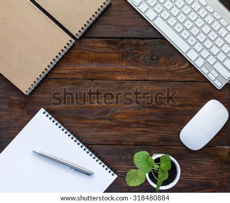 Dark Brown Wooden Desk with Stationery and Electronics\
Square Natural Wood Background Opened and Folded Beige Notepads Small Green Plant  Computer Mouse and Keyboard Top View