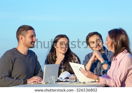 Mixed group in business meeting\
Four People Casual Clothing Sitting Around Wooden Desk and Discussing Looking on Paper Work and Listening Arguments