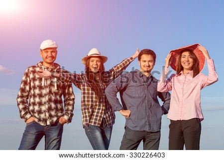 Young Friends Staying and Expressing Positive Emotions\
Four People Men and Women Together on Blue Sky Background Casual Jeans Style Dress Hands Gesturing Smiling Laughing Shining Sun
