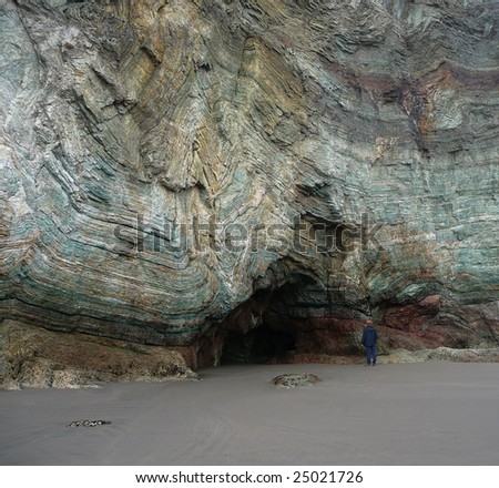 An adult man stands at the opening to a cave at Rainbow Rock in Oregon