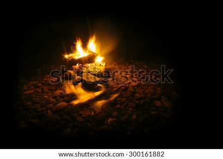 magic fire in the mountain river on the rocks at night. photo framed wholly in black