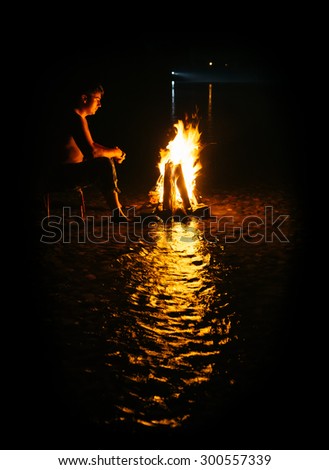 People - Bonfire on the river bank . Sparks, flames and other wonderful backgrounds for your text. photo framed wholly in black.