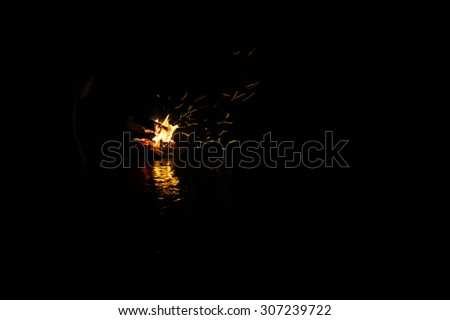 magic fire in the mountain river on the rocks at night. photo framed wholly in black