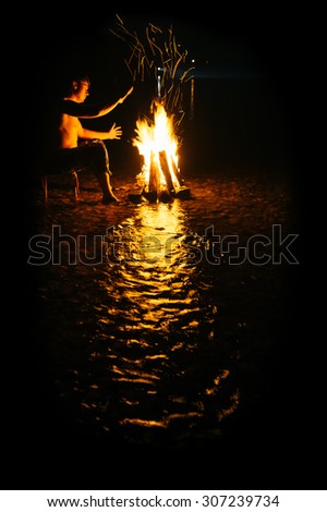 People - Bonfire on the river bank . Sparks, flames and other wonderful backgrounds for your text. photo framed wholly in black.