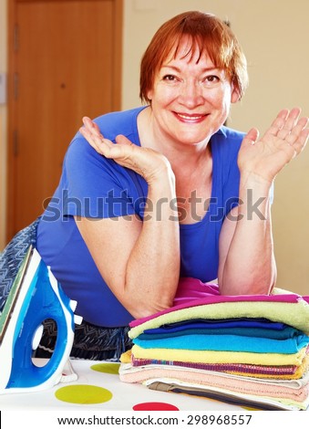 Happy woman ironing clothes on an ironing board
