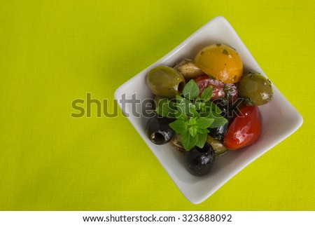 Mediterranean antipasti salad with mozzarella balls, green and black olives and cherry tomatoes and some tiny-leafed basil.