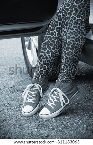 The woman rising out of the car with blue sneakers in Finland. He is wearing a leopard-print pants. Image includes a black and white effect.