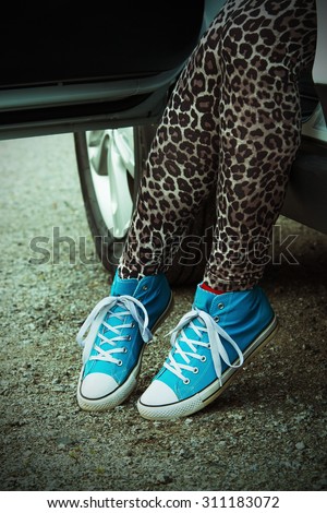The woman rising out of the car with blue sneakers in Finland. He is wearing a leopard-print pants. Image includes a lomo-blue effect.
