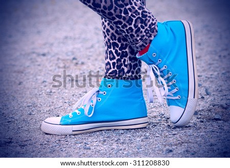 Woman\'s legs in blue sneakers in Finland. She is wearing a leopard-print pants. Image includes a effect.