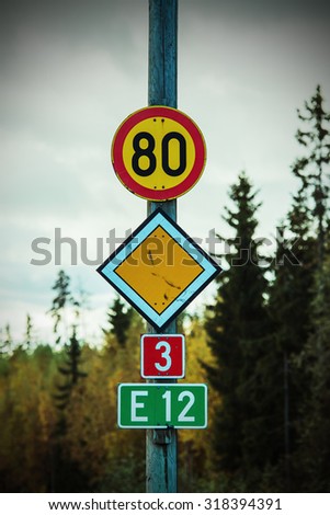 Traffic signs on the road in Finland. Winter speed limit 80 km/h marked on the top. Image includes a effect.