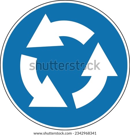 Roundabout direction sign. Mandatory sign. Round blue sign. Drive around the flowerbed (central island) in the direction shown by the arrows at the roundabout. Road sign.