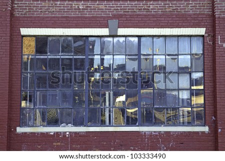 A large street window with a multitude of small panes of glass with brick wall.