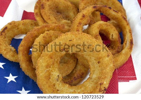 Close view of several hot onion rings on red white and blue flag motif napkins.