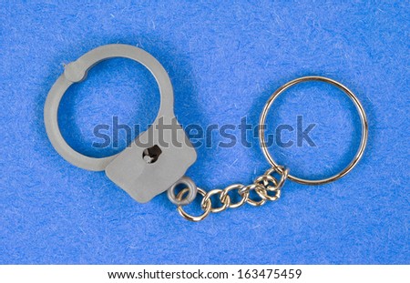 A toy key chain shaped as handcuffs on a blue background.