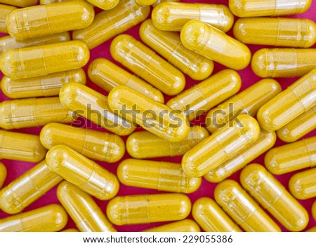 Close view of a group of turmeric herbal capsules on a red background.