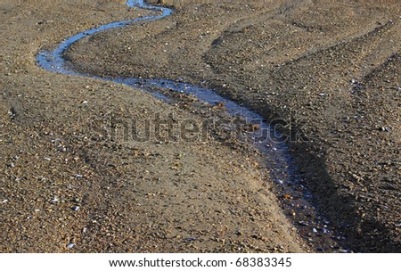 A small stream of salt water flowing towards the ocean at low tide.