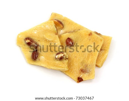 Several pieces of peanut brittle on a white background.