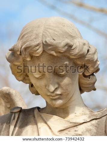 The face of a sad angel statue in downward cast.