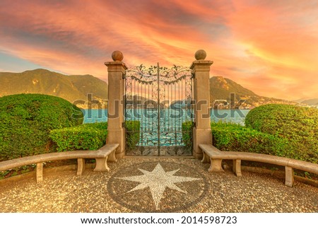 Gate on the Lugano Lake in the public Ciani park of Switzerland. Red sunset by the lakefront of Lugano city in Ticino canton. Park bench with wind rose of stones and with Monte San Salvatore mount. Zdjęcia stock © 