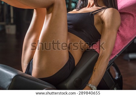 An athletic woman exercising on a leg press.