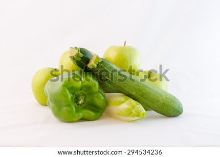 Composition consisting of two courgettes, four apples, a pepper and a endive, all green. White background, isolated.