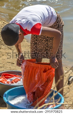 UMkhuze Game Reserve, South Africa - August 24, 2014: African woman washing clothes in the river on the road leading to UMkhuze Reserve