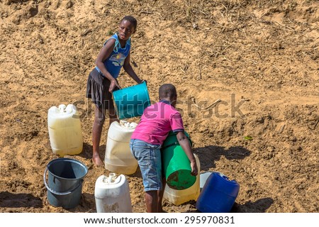 UMkhuze Game Reserve, South Africa - August 24, 2014: African children collecting water from the river with tanks and buchets, on the road to reserve
