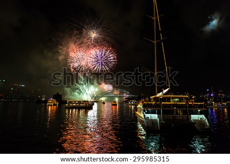 Sydney, Australia - December 31, 2014: Spectacular midnight fireworks to celebrate the new year, seen from the boat in a windy and cloudy sky.  View of Opera House theater and Harbor Bridge from sea.