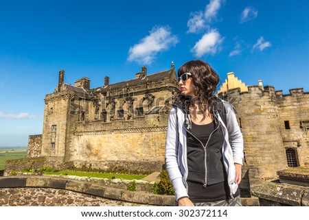 Young tourist woman standing in front of the famous Stirling Castle, in Stirling town, Central Scotland, UK, Europe on a sunny day.
