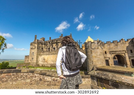 Young tourist woman observes the famous Stirling Castle, in Stirling town, Central Scotland, UK, Europe on a sunny day.