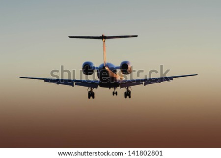 rear view silhouette of private corporate jet in flight at sunset