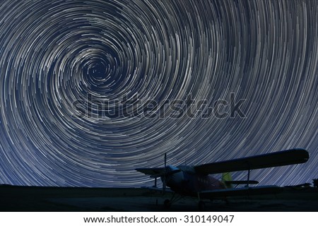 Beautiful night sky, Spiral Star trails over small airport lonely airplane. Vortex Star trails.
