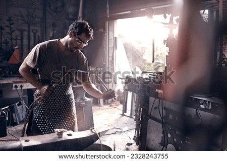 Similar – Image, Stock Photo Focused young blacksmith heating and striking metal on anvil in workshop