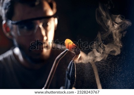Similar – Image, Stock Photo Focused young blacksmith heating and striking metal on anvil in workshop