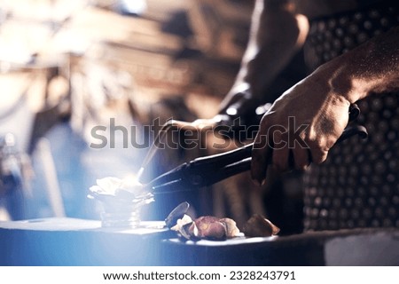 Similar – Image, Stock Photo Focused young blacksmith heating and striking metal on anvil in workshop
