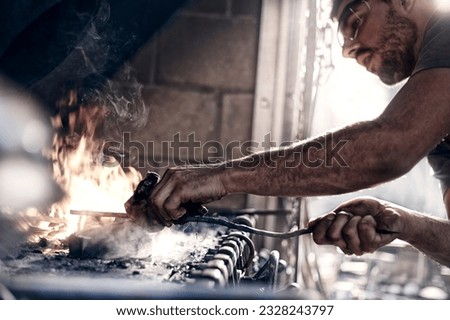 Similar – Image, Stock Photo Focused young blacksmith heating and striking metal on anvil in workshop
