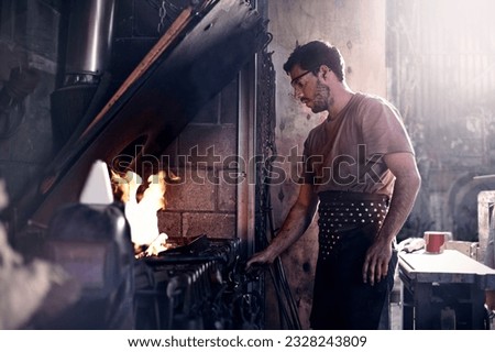 Similar – Image, Stock Photo Focused young blacksmith heating and striking metal on anvil in workshop