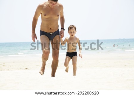 Father and his son run on the beach