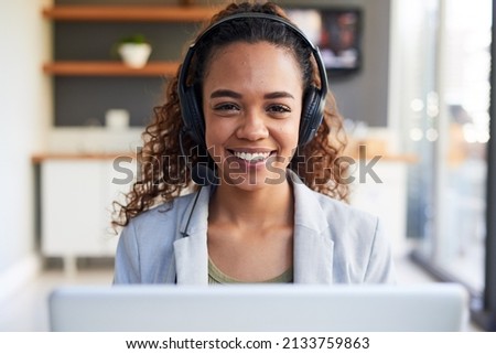 A centred view of a young woman behind her laptop with headset in modern office Foto d'archivio © 