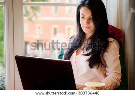 Girl sitting near the window with a laptop