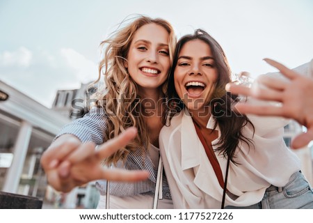 Lovable caucasian girls expressing positive emotions to camera. Outdoor photo of refined sisters posing on sky background. ストックフォト © 