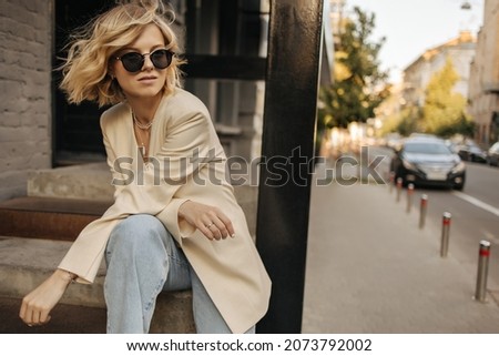 Similar – Image, Stock Photo Blonde woman wearing denim shirt and black leather skirt sitting in an urban bench.