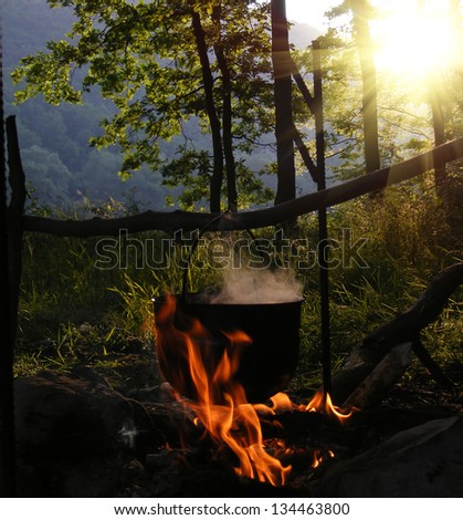 Smoky tourist kettle on fire in morning forest