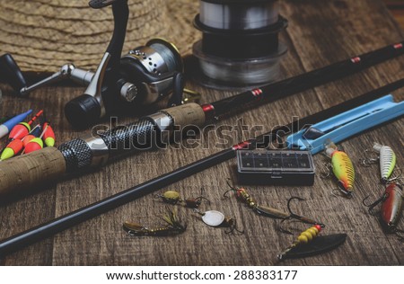 Fishing tackle - fishing rod, fishing line, hooks and lures on wooden background