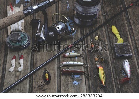 Fishing tackle - fishing rod, fishing line, hooks and lures on wooden background