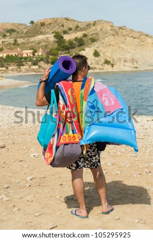 Guy loaded with all sorts of stuff on his way to the beach